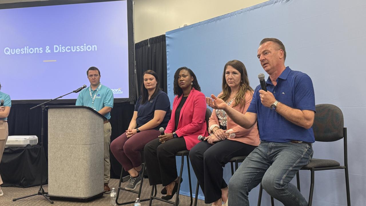 A group of panelists sit next to one another on stage during a panel discussion at the World Pork Expo