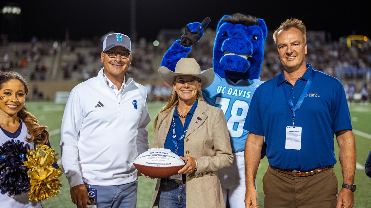Ashley Stokes receives the game ball from Dr. Frank Miloehner