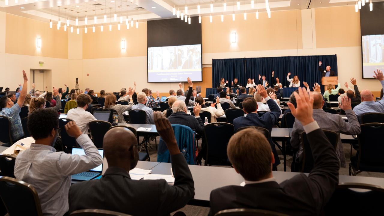 State of the Science Summit attendees raise their hands.