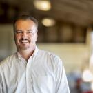 Frank Mitloehner is wearing a white button up shirt and smiling at the camera