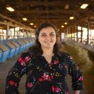 alice rocha standing in front of feed lot stalls with arms at side